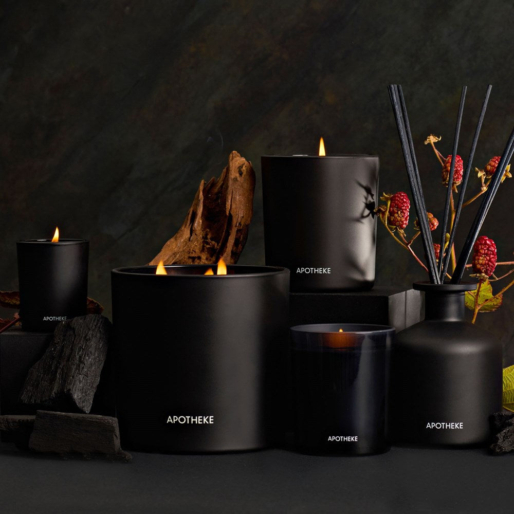 APOTHEKE Charcoal candles and diffuser styled against a dark backdrop